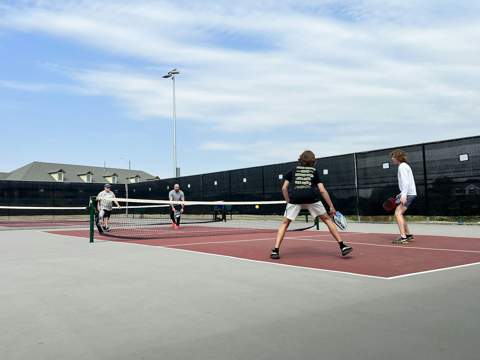 Un grupo de jugadores de pickleball reunidos en la pista — la comunidad es el corazón de la etiqueta del pickleball