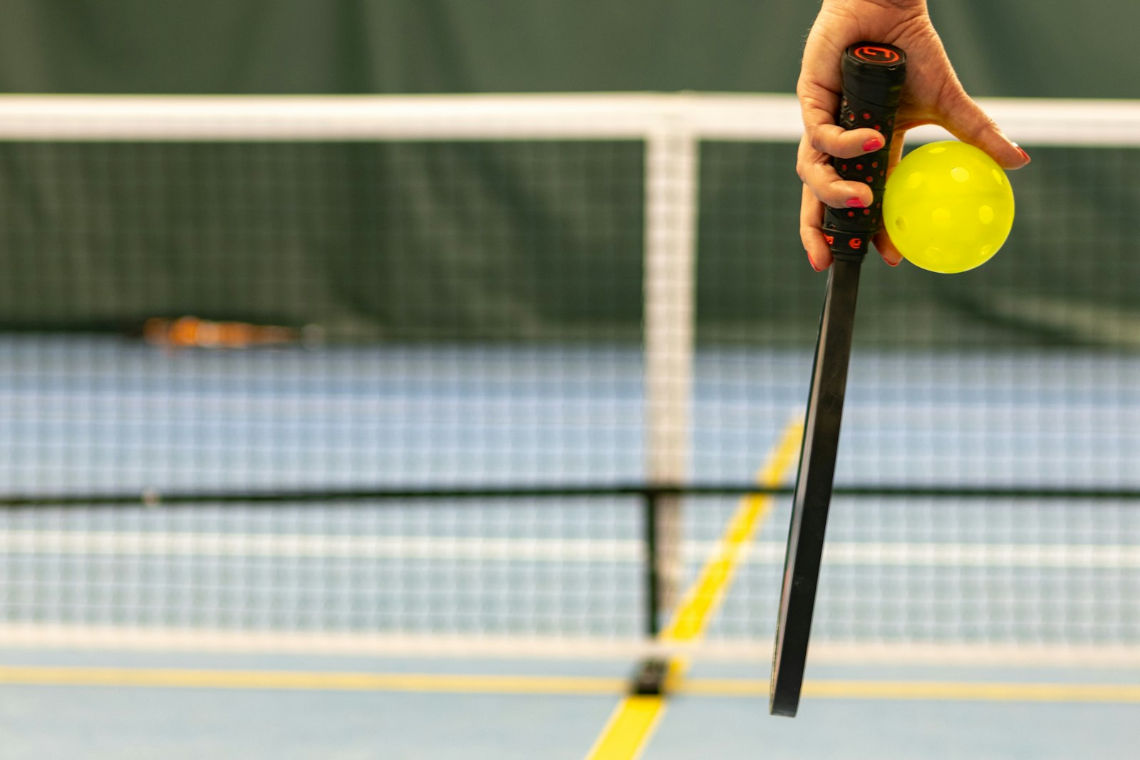 Primer plano de una mano envolviendo el mango de una pala de pickleball