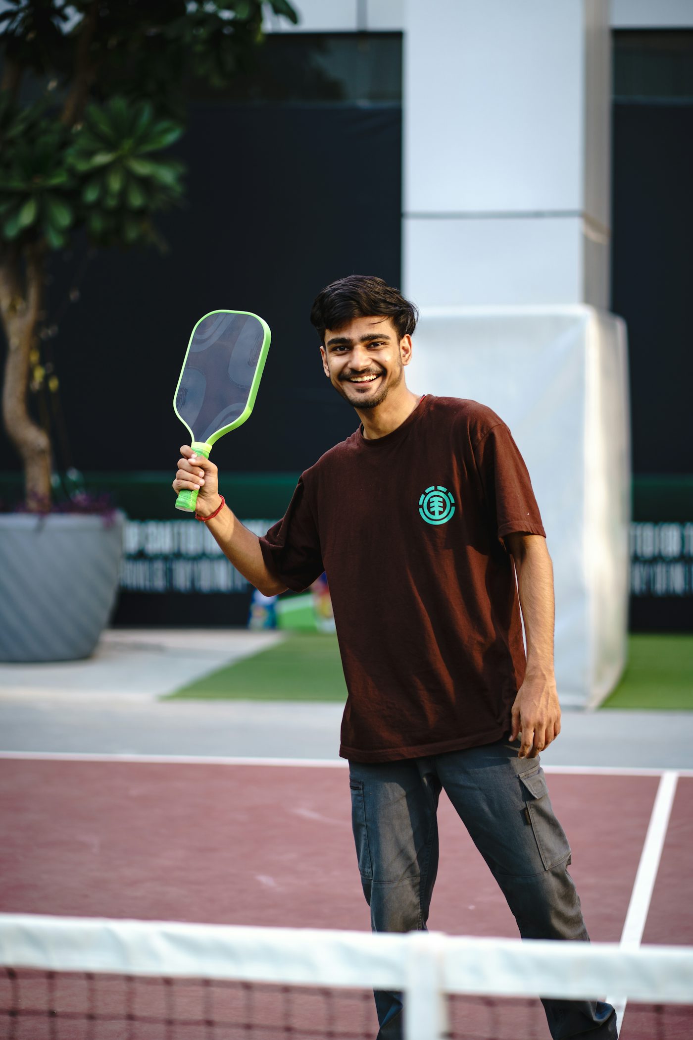 Smiling pickleball player holding a paddle on an outdoor court — the giftable-lifestyle feel that fits a stocking-stuffer gift guide